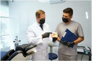 dentist pointing to a tooth model while mentoring a colleague in a dental office.