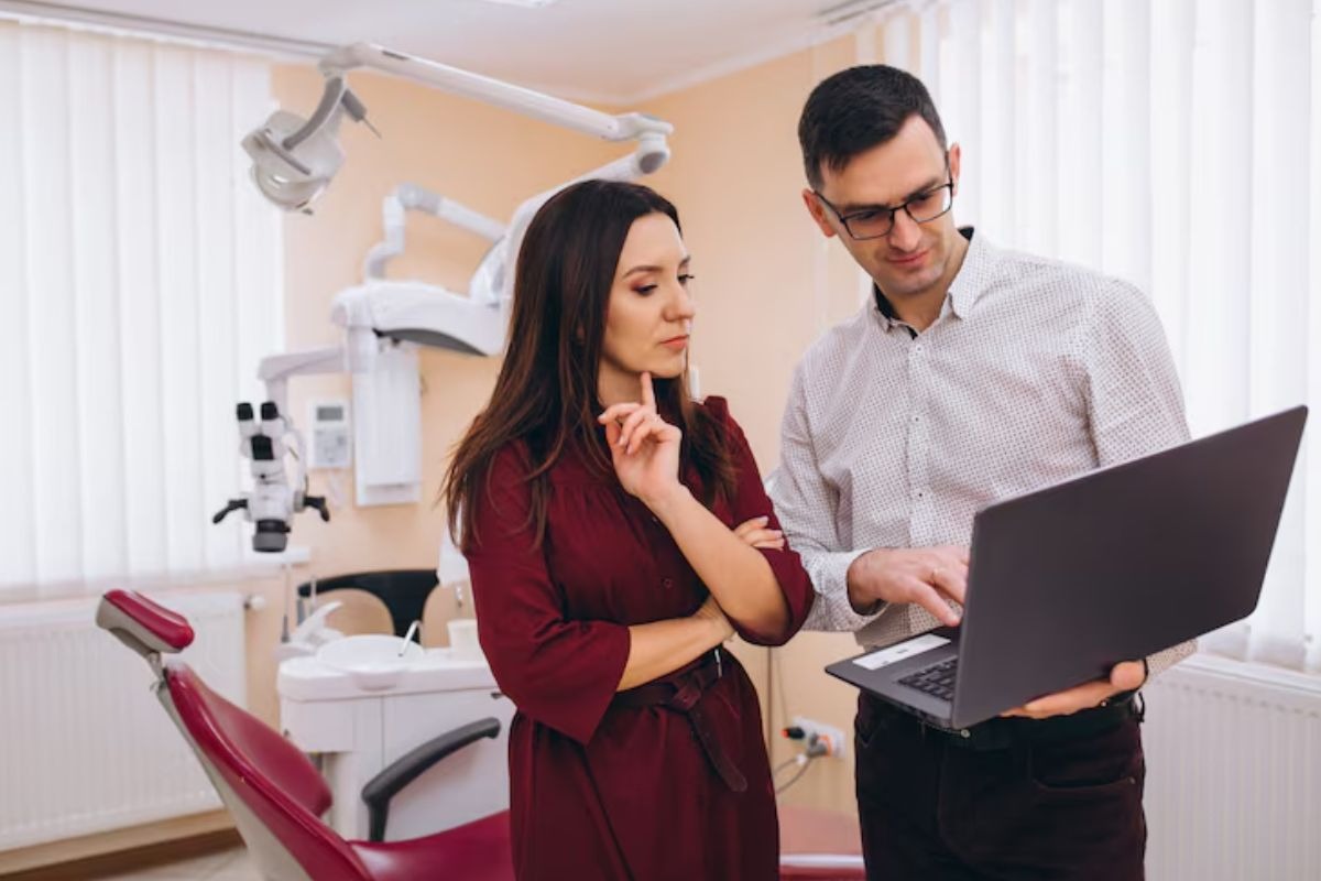 dentist and colleague reviewing practice management strategies on a laptop.